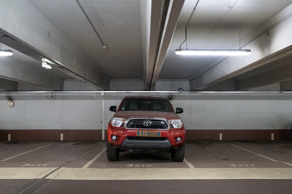 Plaque 6 CD — États-Unis, corps diplomatique (Toyota Tacoma) Plaque diplomatique verte 6 CD sur un Toyota Tacoma rouge garé dans un parking souterrain — code 6 correspondant aux États-Unis