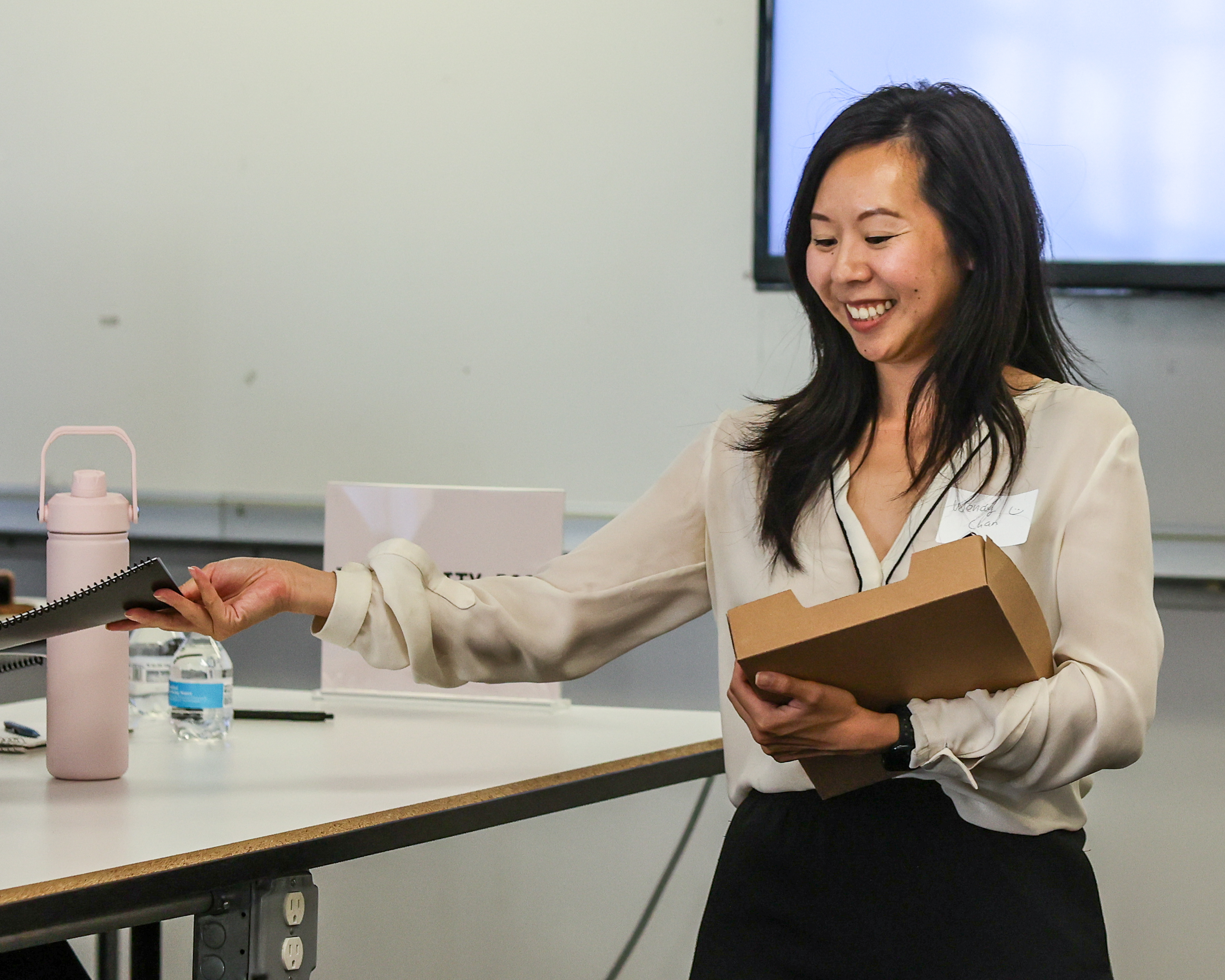 Wendy Chan smiling while handing out workshop materials to a participant