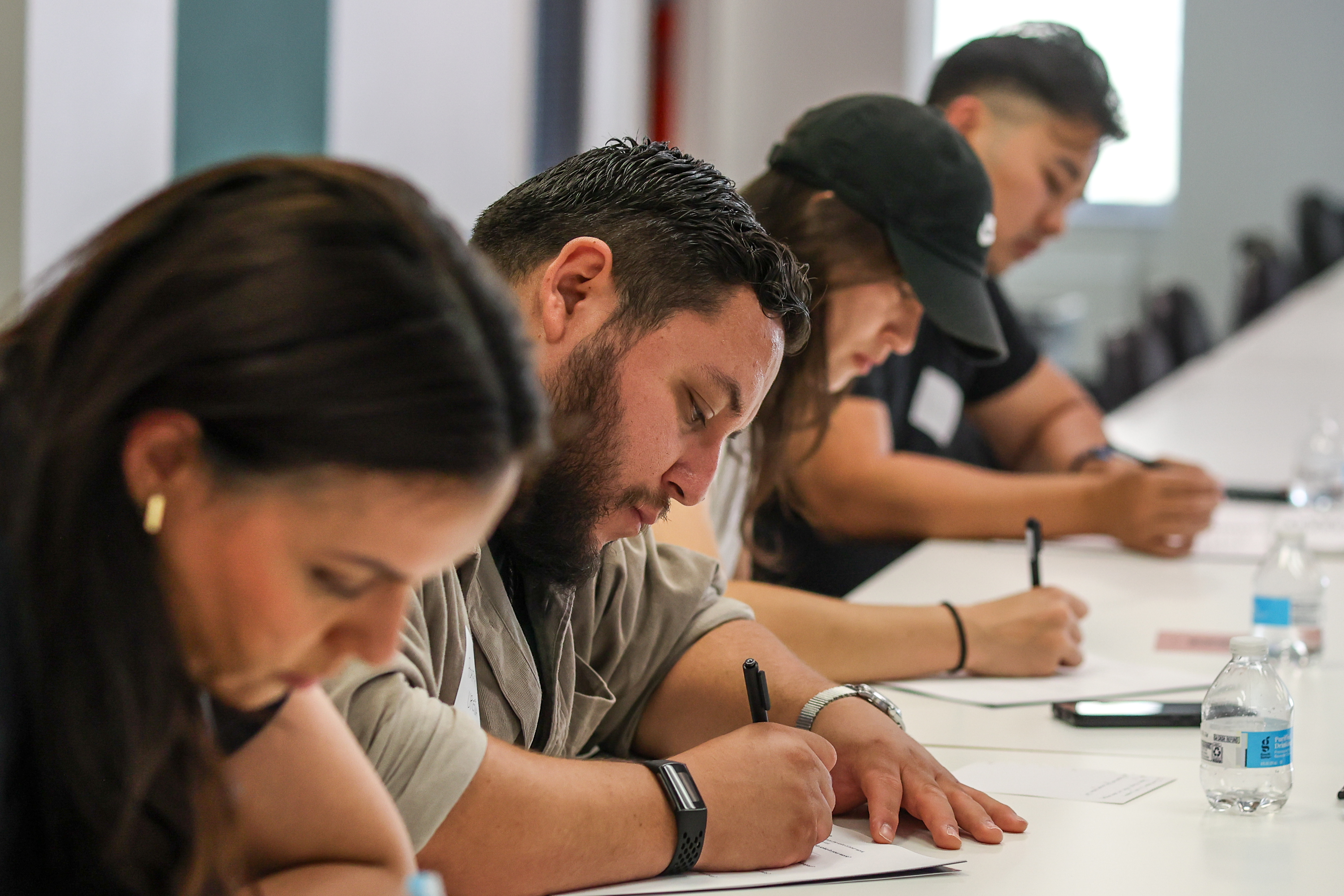 Close-up of attendees writing in their workbooks along a table