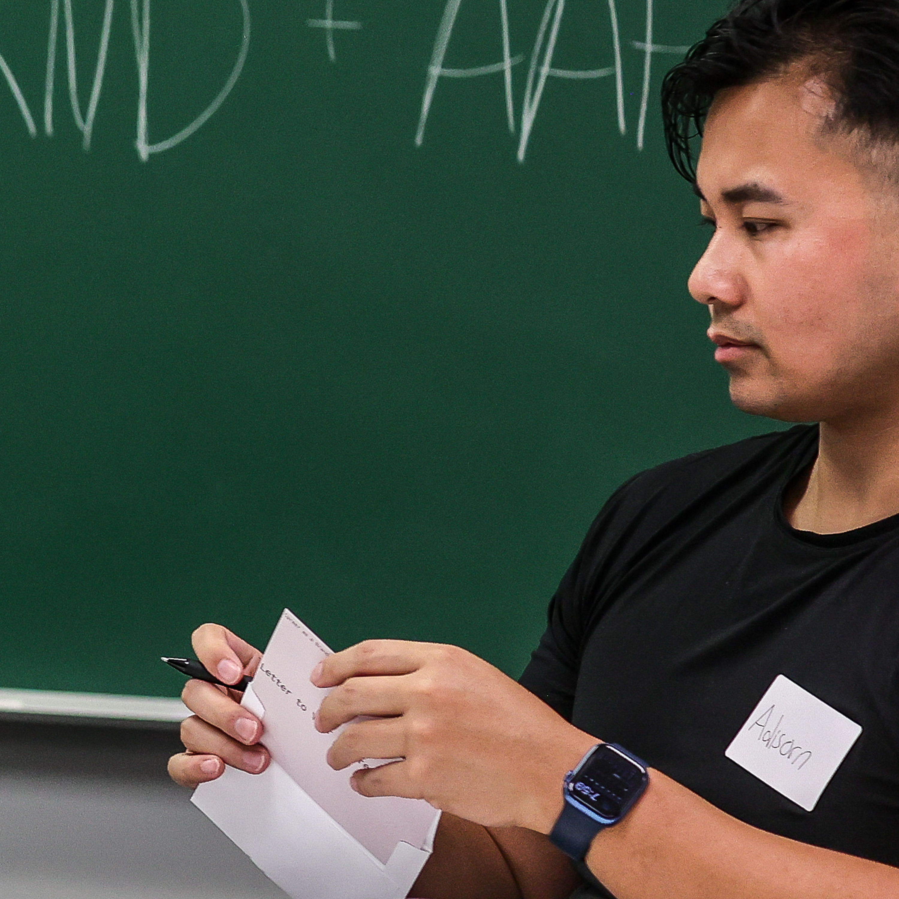 An attendee writing on a Letter to Your Future Self envelope at the chalkboard