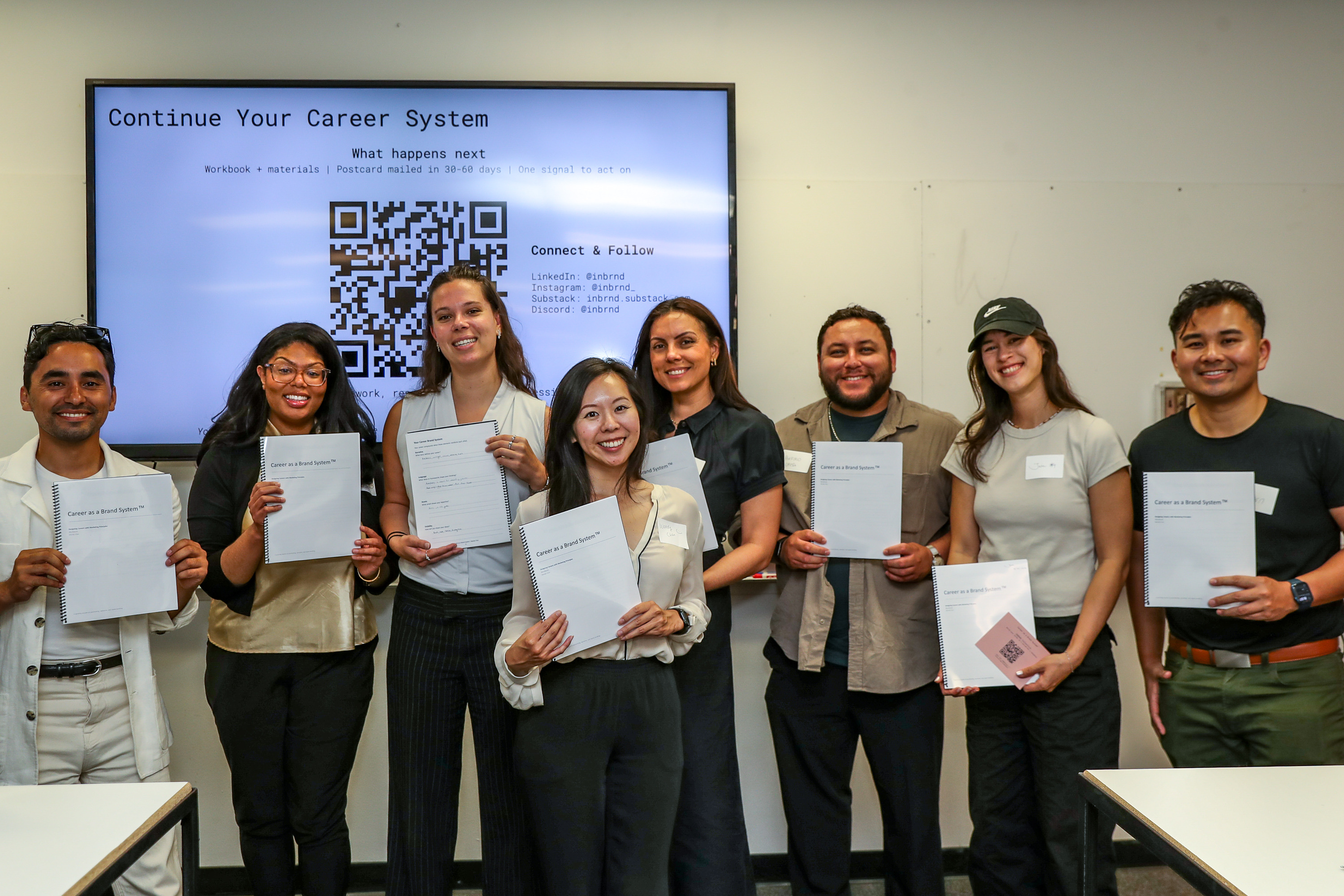 Group photo of the eight participants holding their Career as a Brand System workbooks