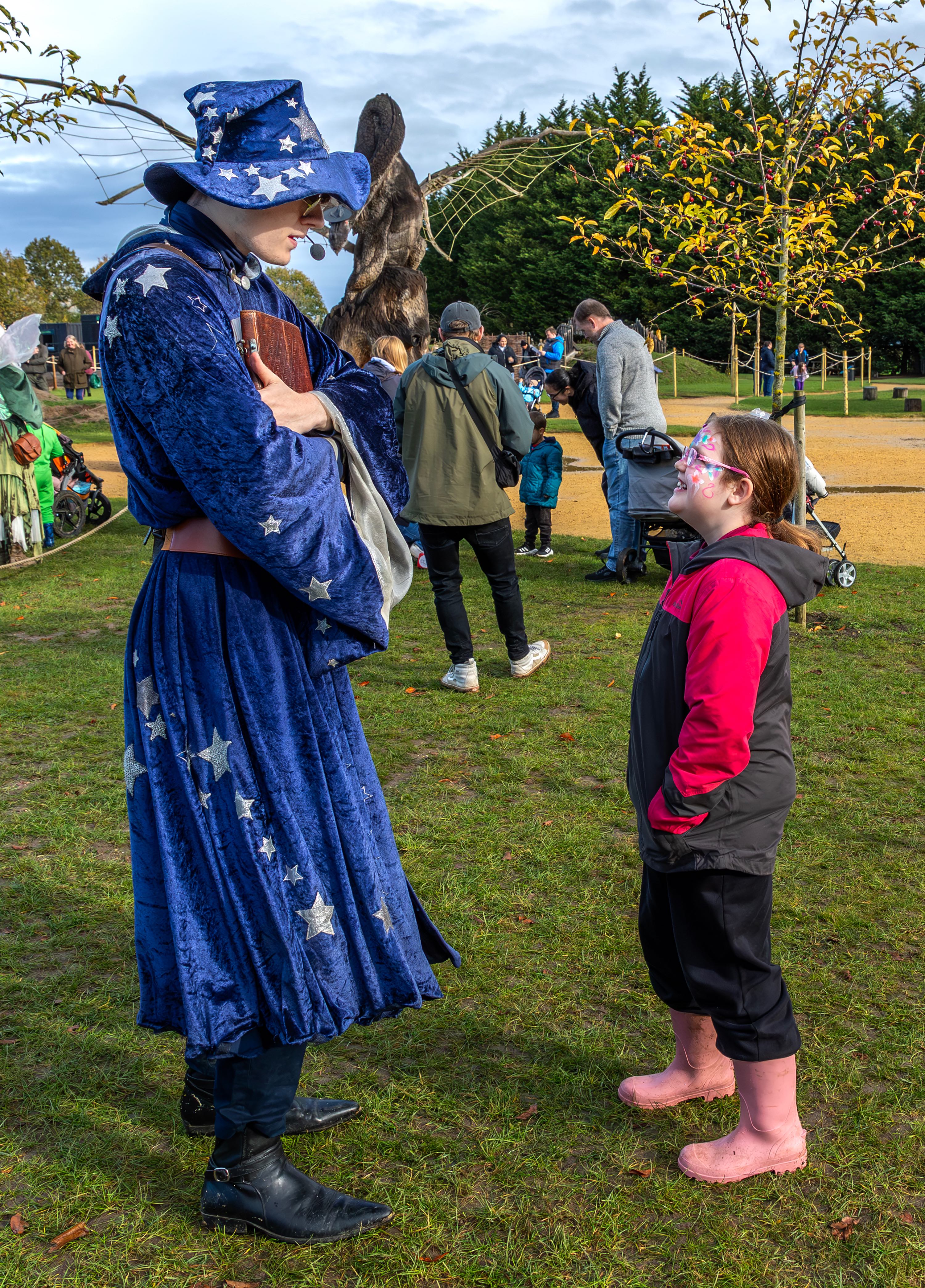 Child with face paint smiling at a wizard character in blue star robe at Wyvernwood SEND Fest