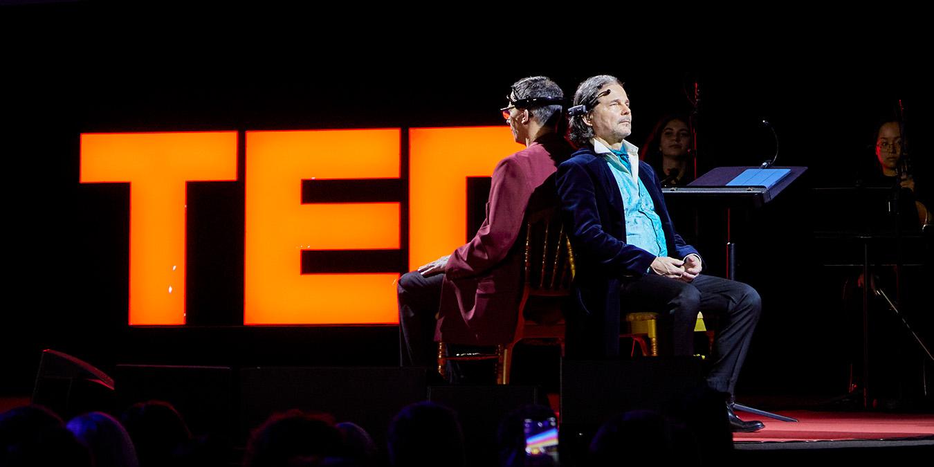 Walter Werzowa and Olivier Oullier on stage at TED wearing brain-sensing headsets, demonstrating brain-controlled music