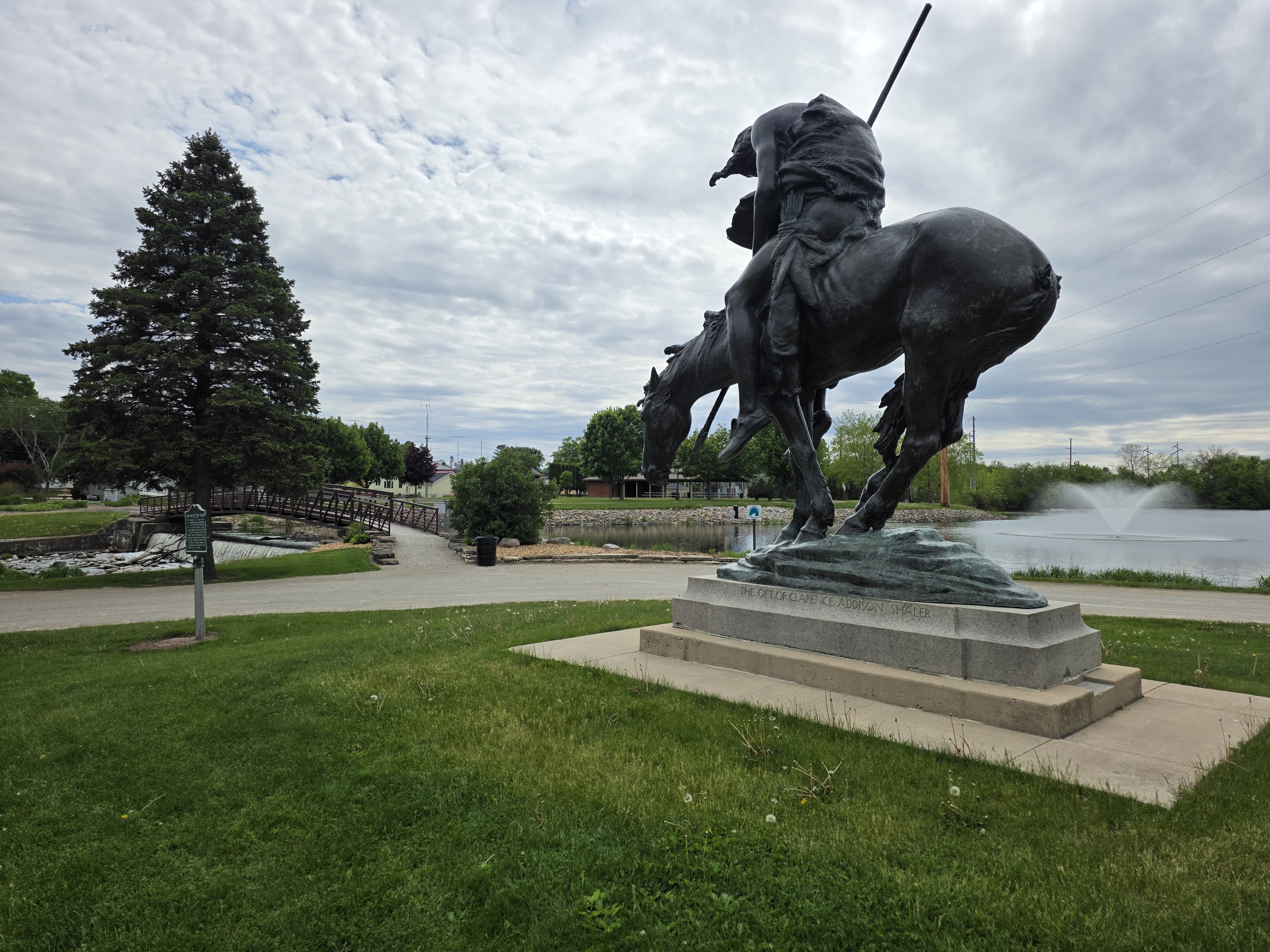 Flat Iron Park in Waupun, WI featuring the iconic equestrian statue, pond, and footbridge