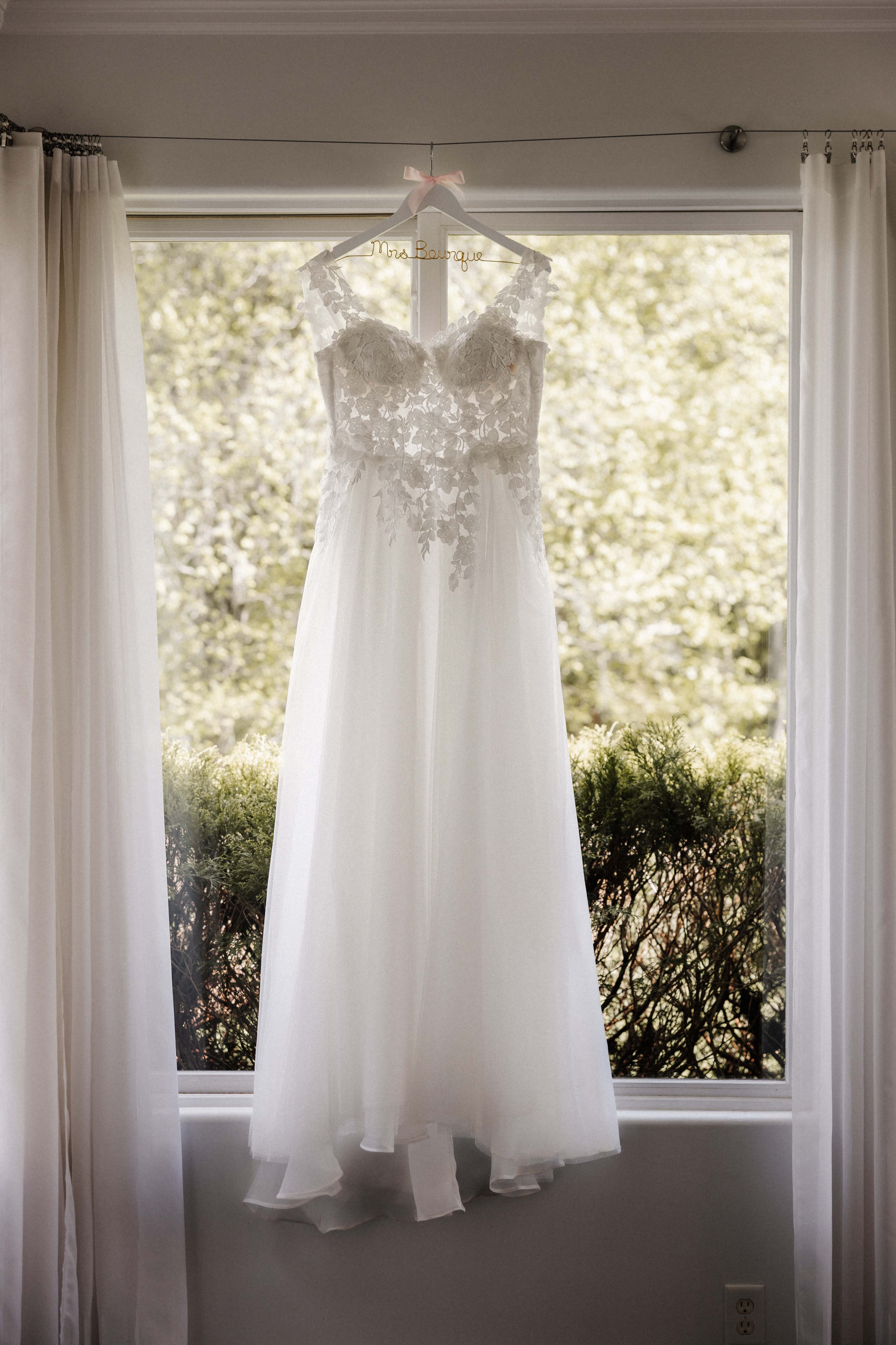 Wedding dress hanging in window with custom Mrs. name hanger