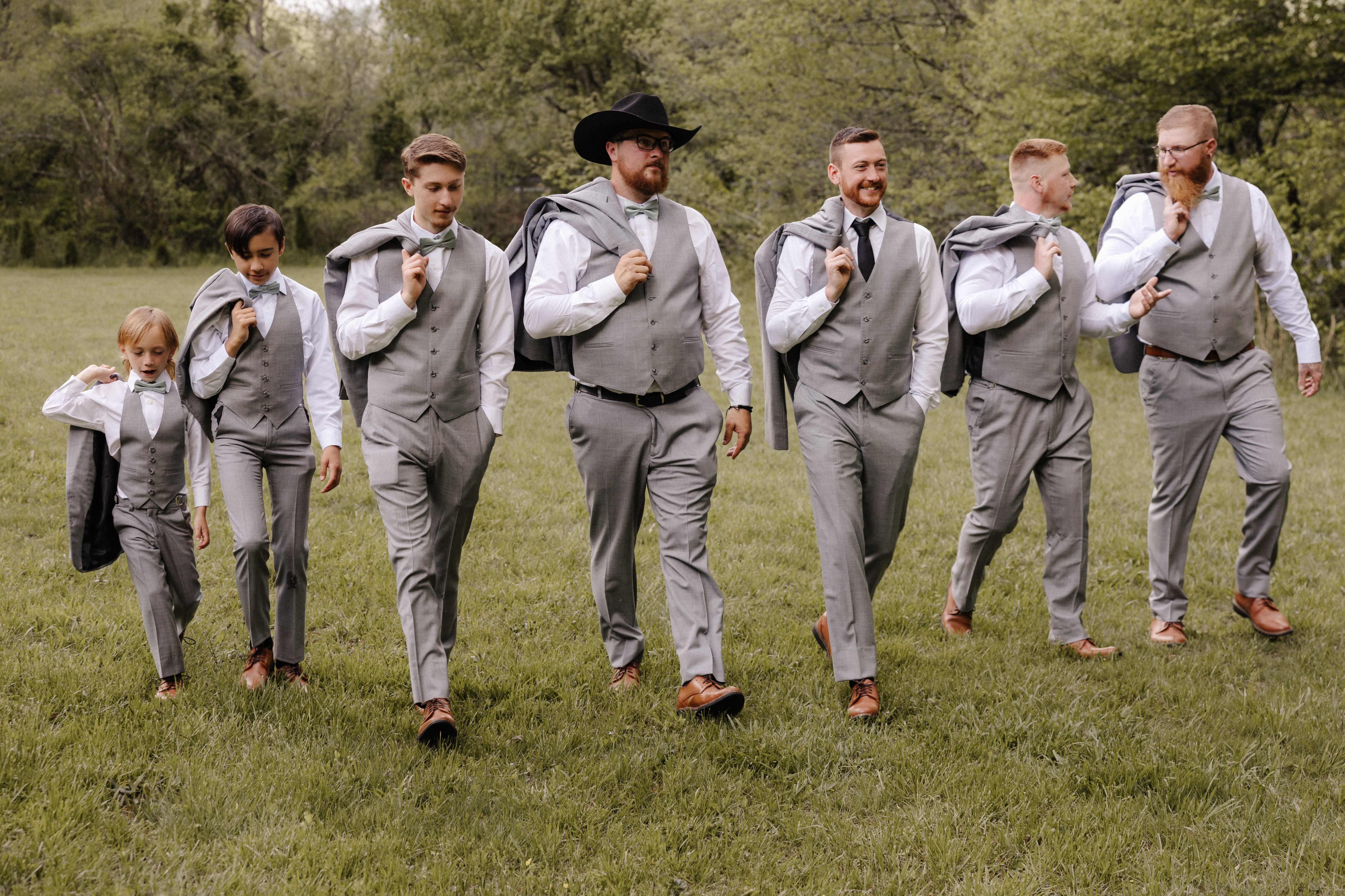 Groomsmen walking with jackets over shoulders in gray suits