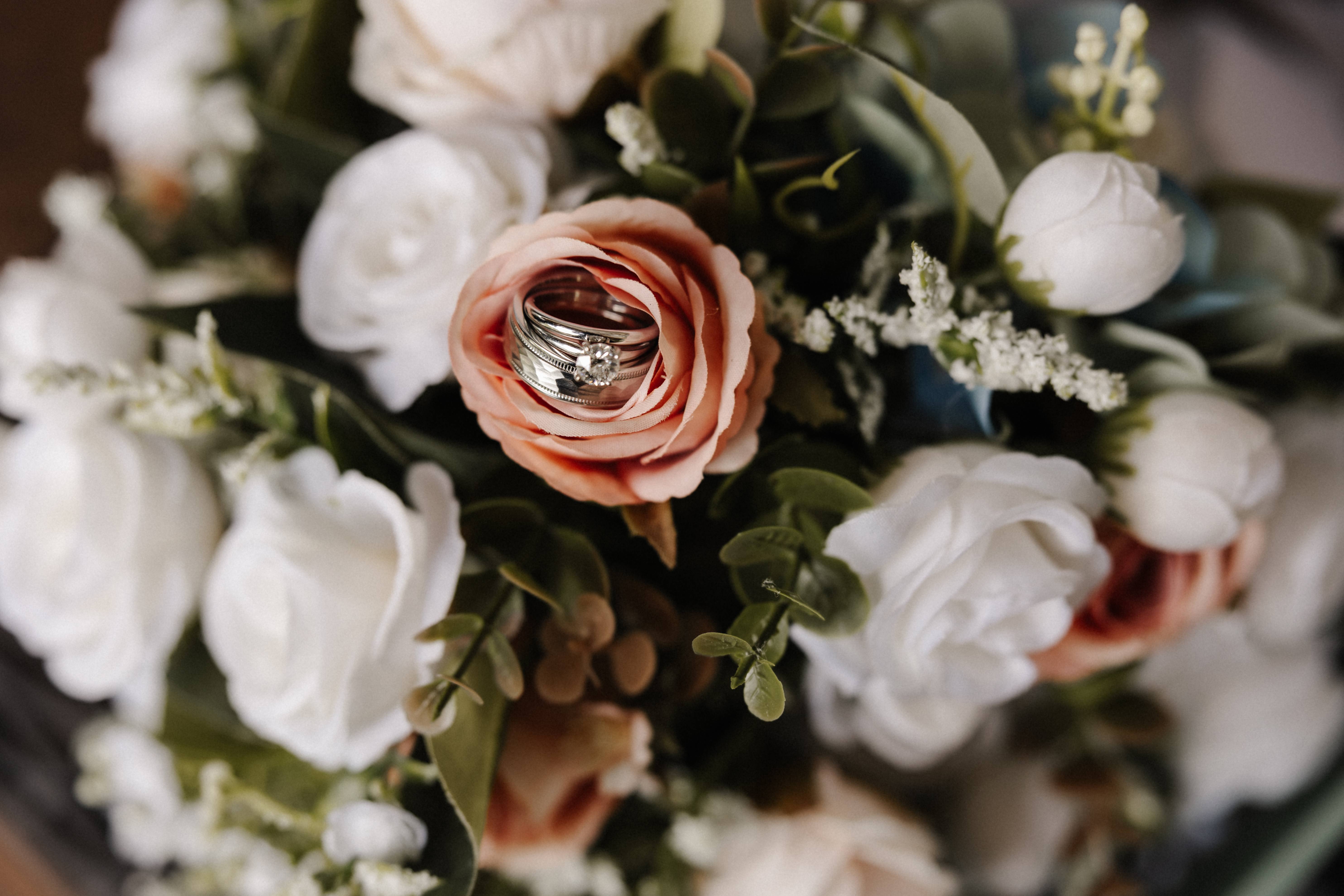 Wedding rings nestled in pink rose on bouquet