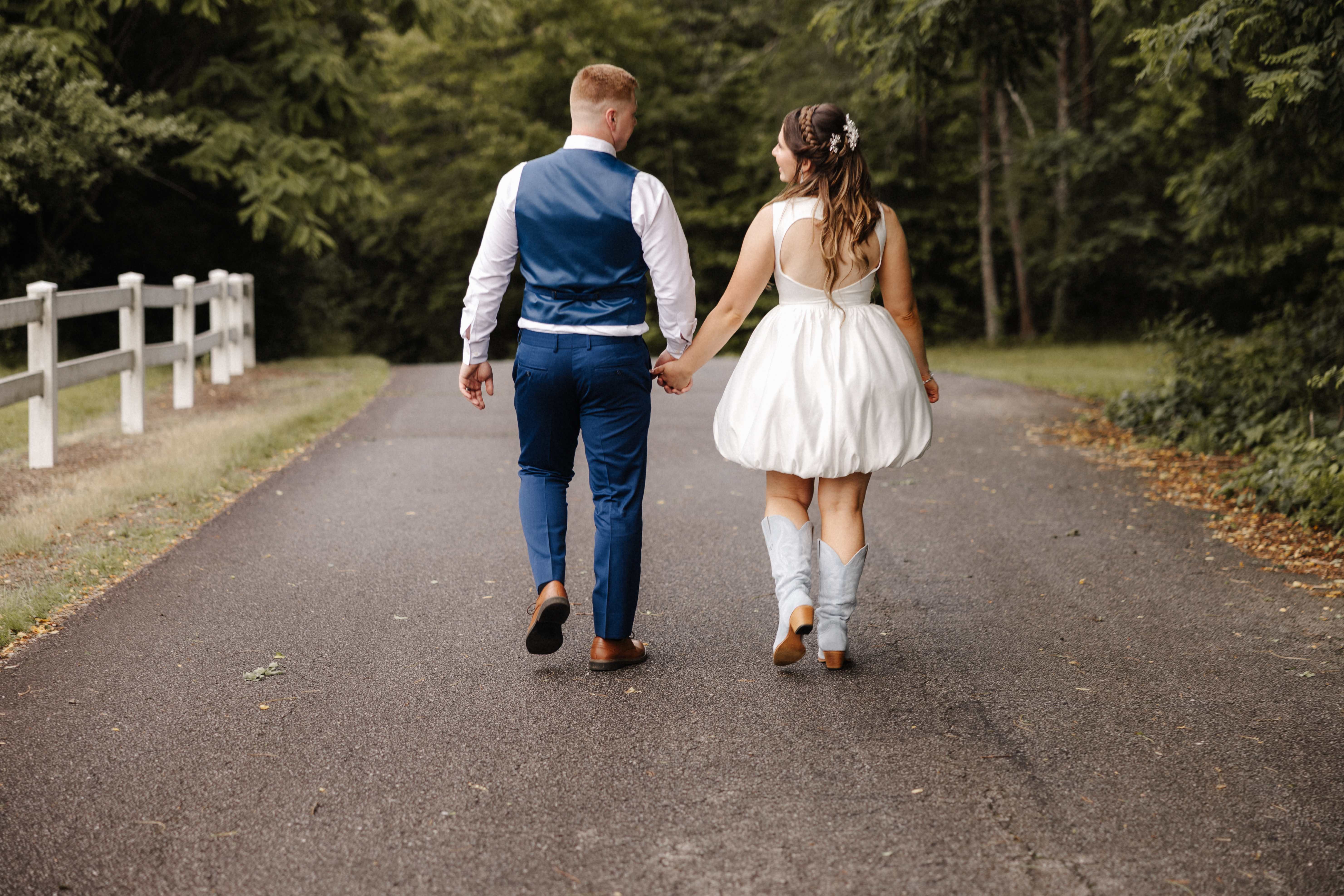 Couple walking away holding hands with bride in blue cowboy boots