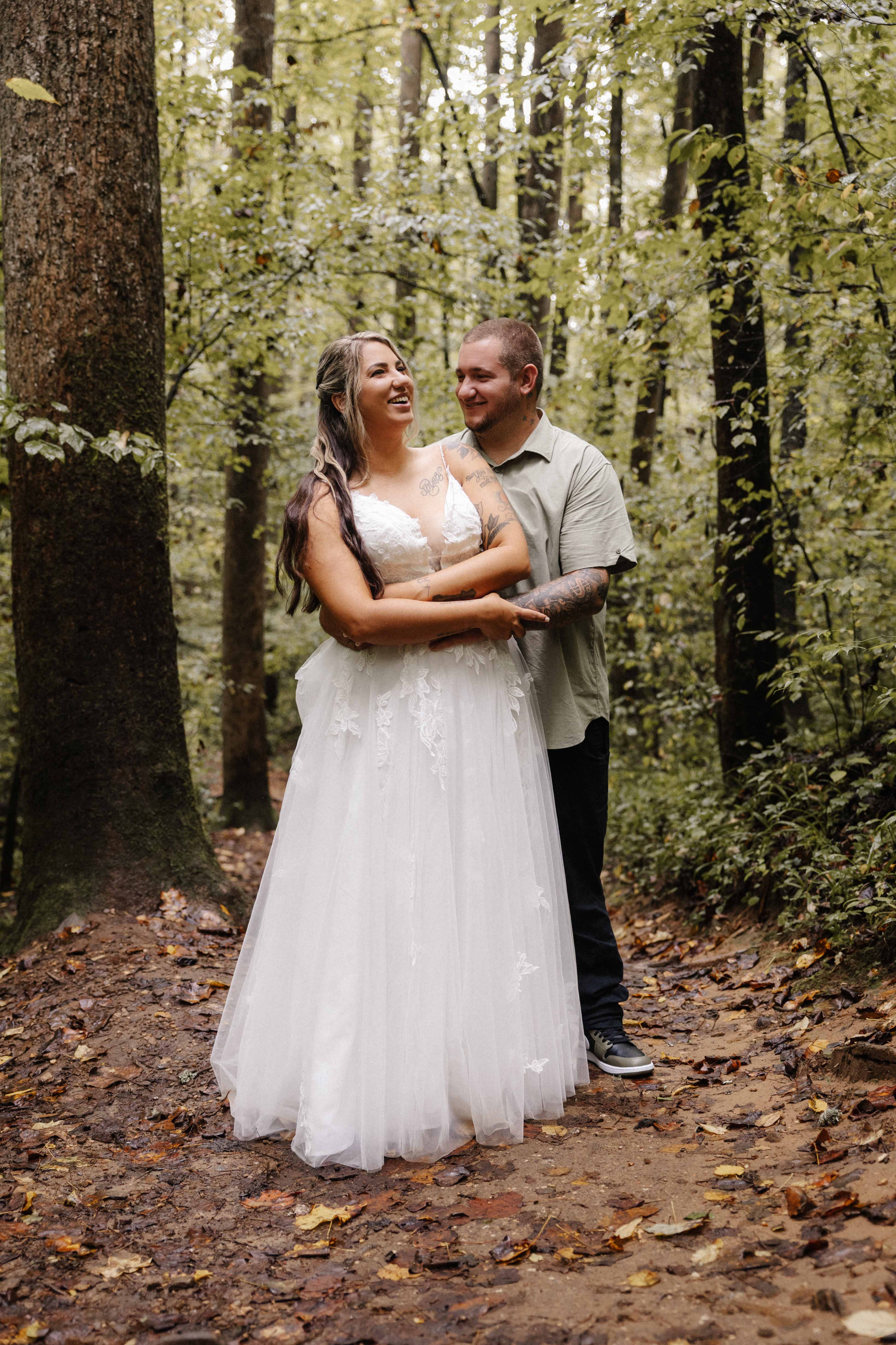 Couple laughing together on forest path with fall leaves