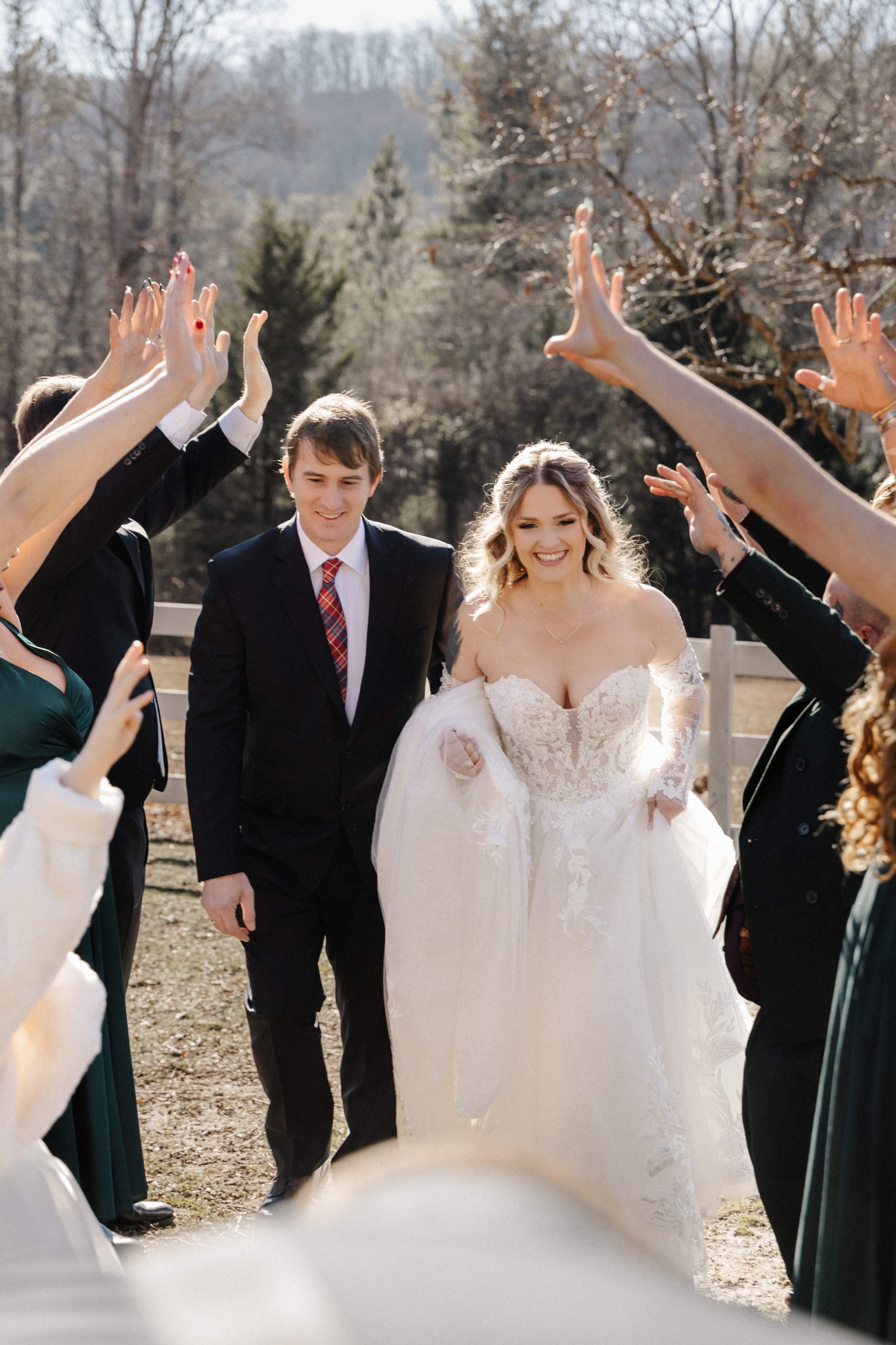 Wedding party forming hand tunnel for couple walking through