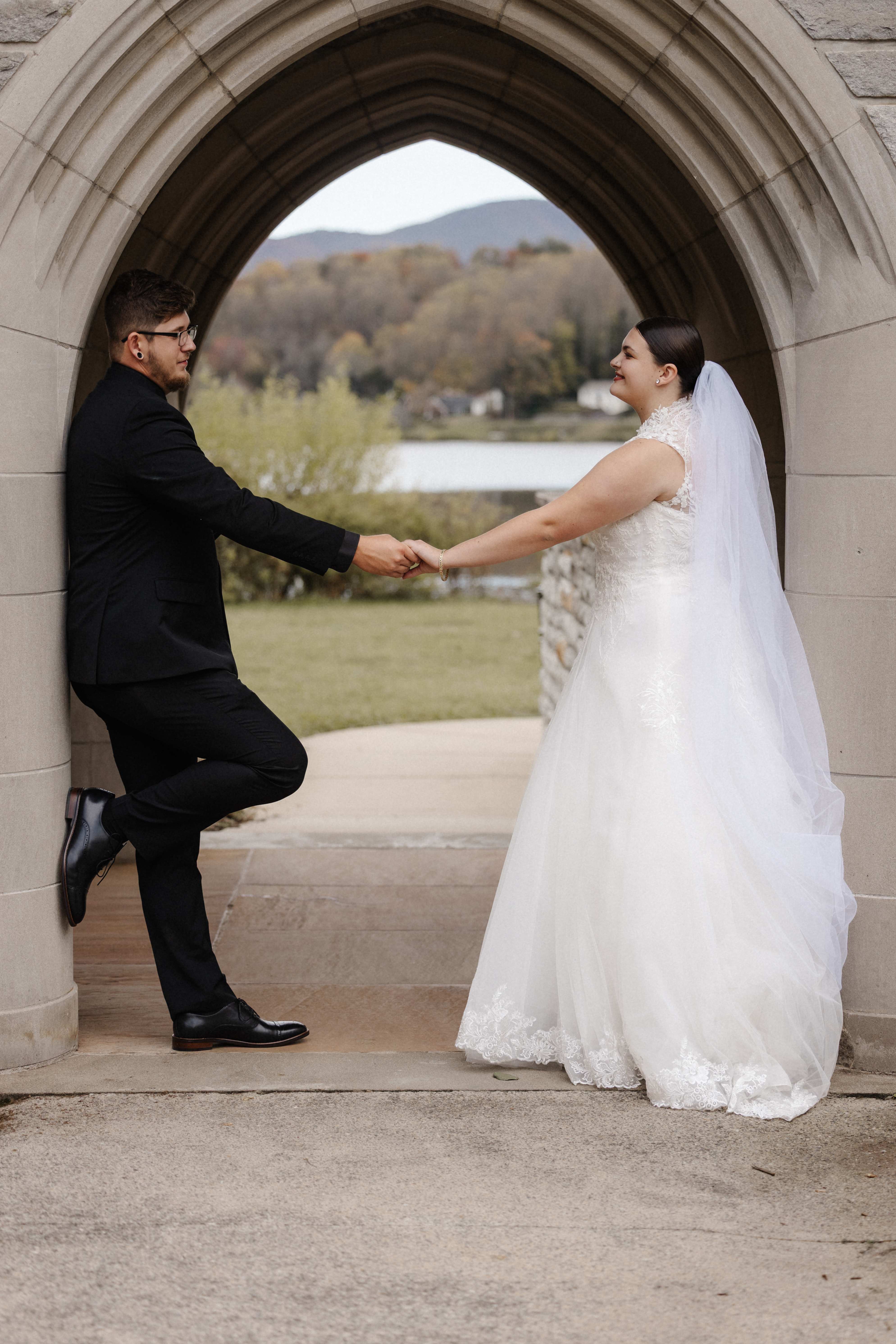 Couple in gothic stone archway with mountain lake view behind