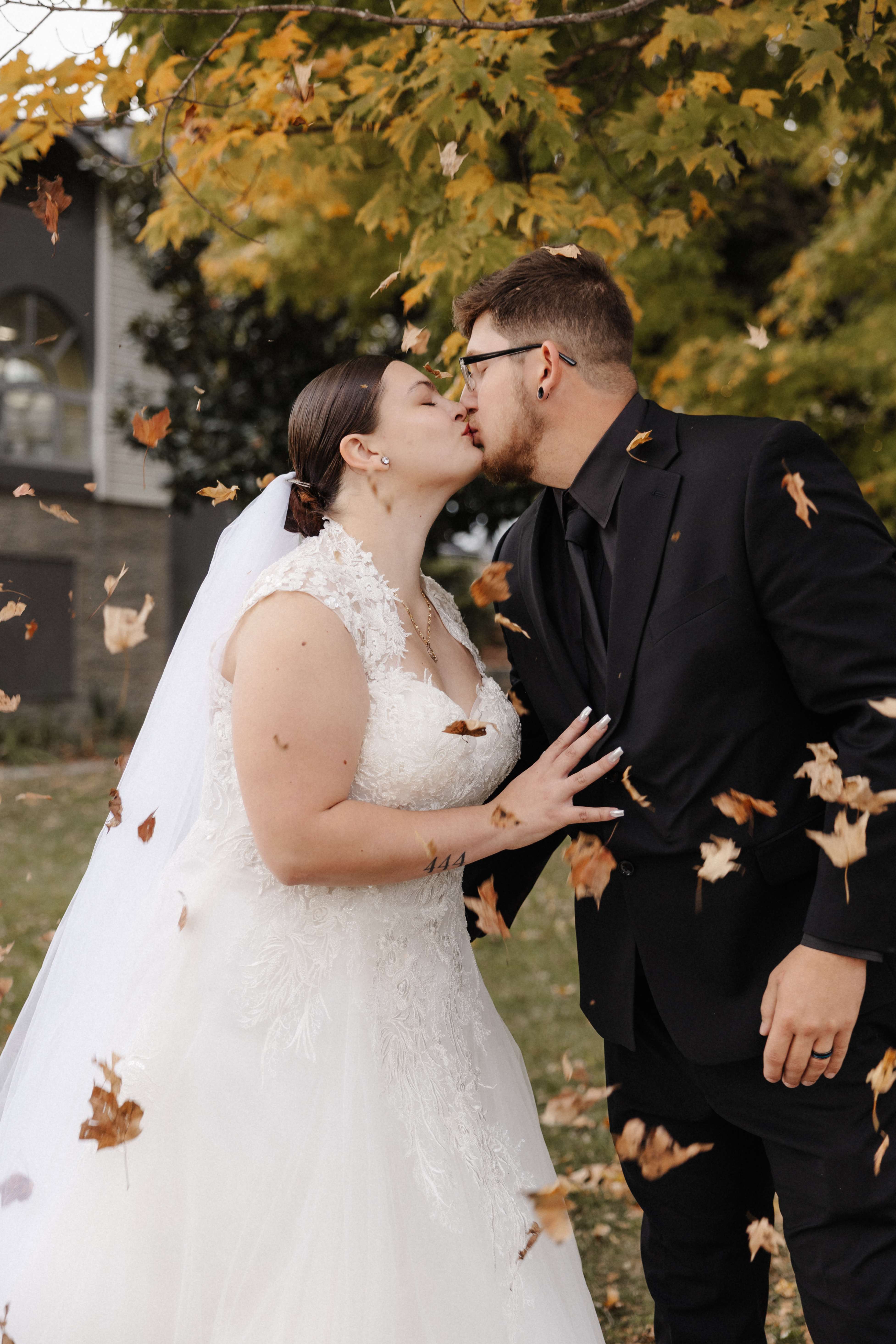 Couple kissing with fall leaves flying around them