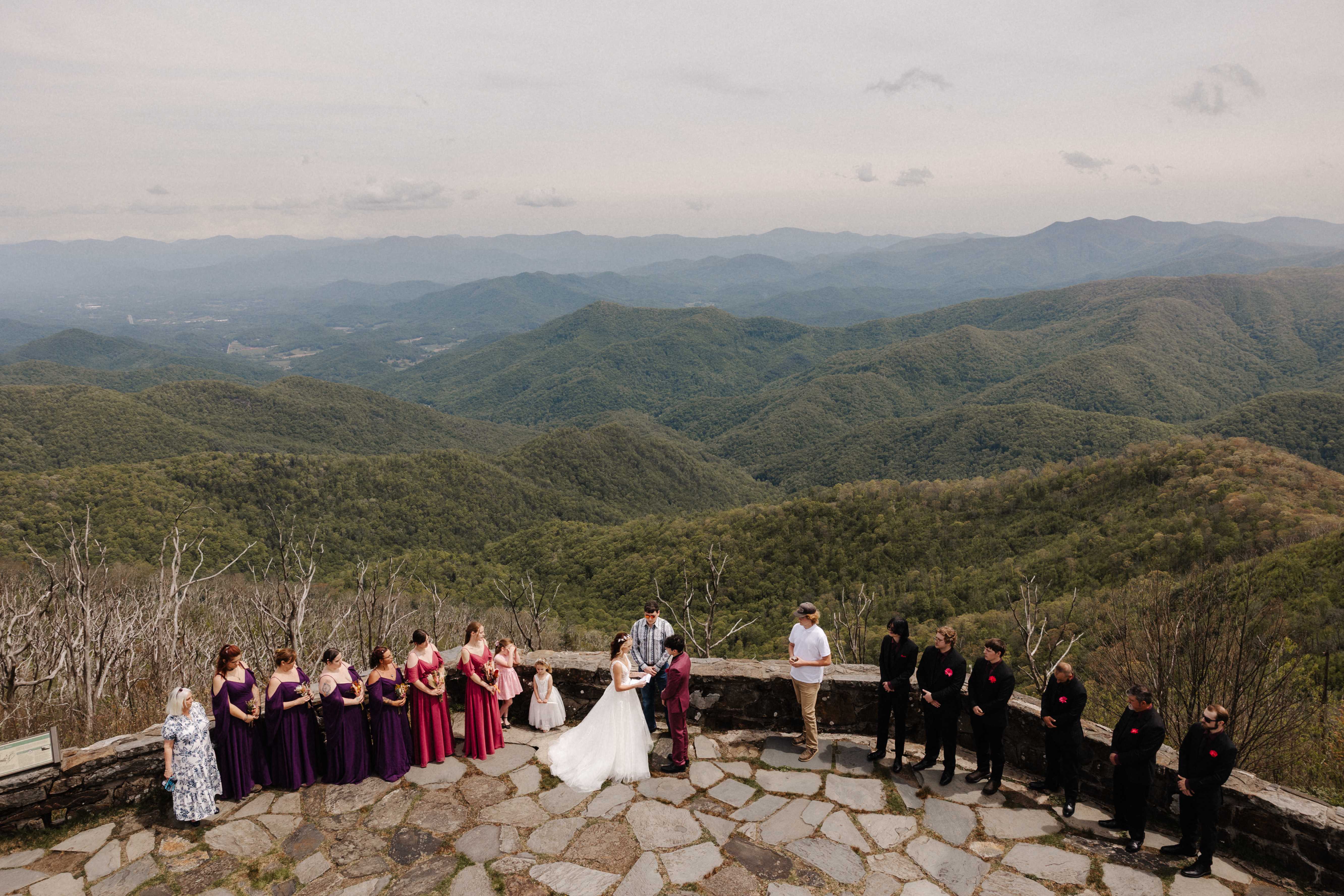 Wide shot of ceremony at mountain overlook with wedding party