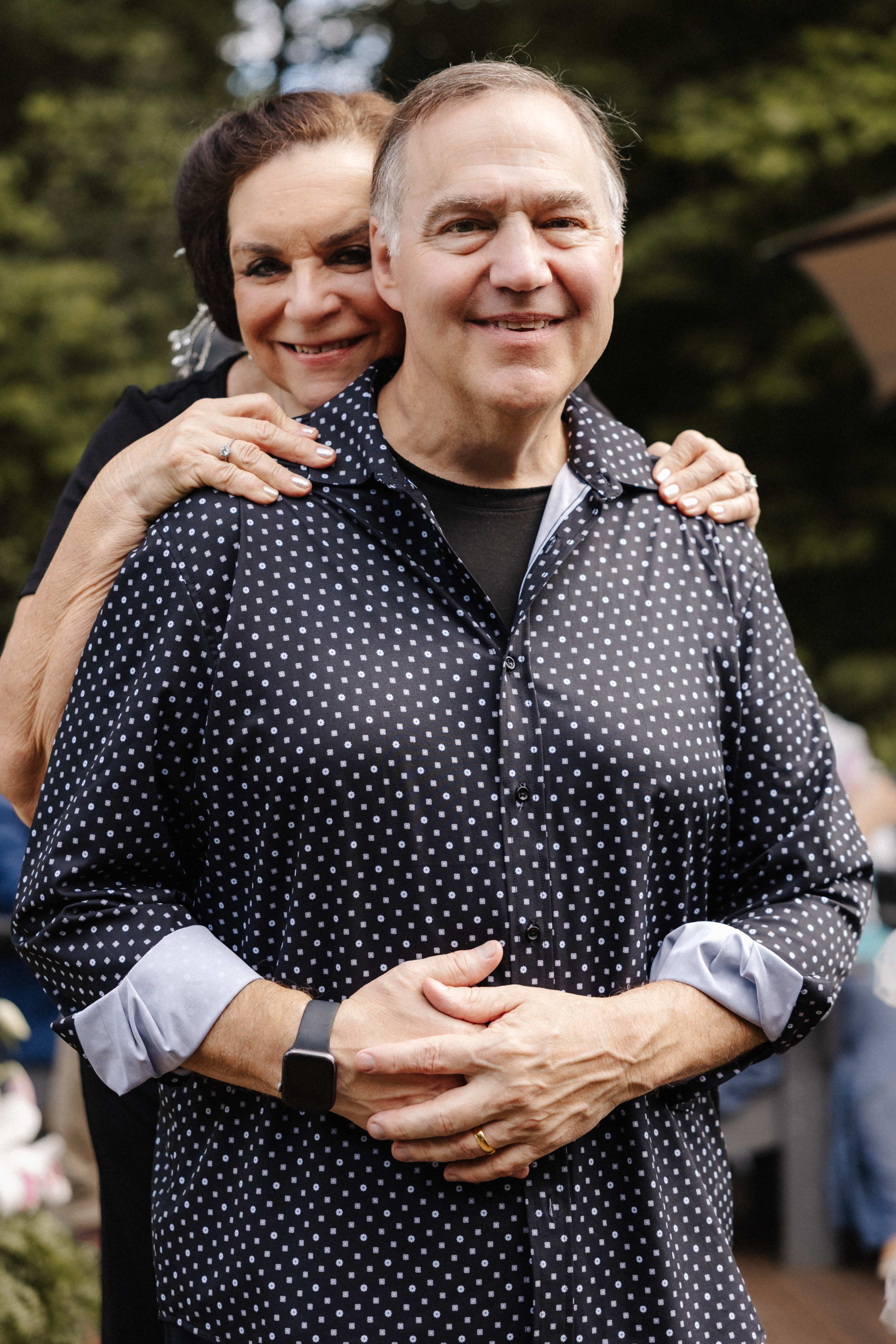 Couple portrait with wife embracing husband from behind in matching navy