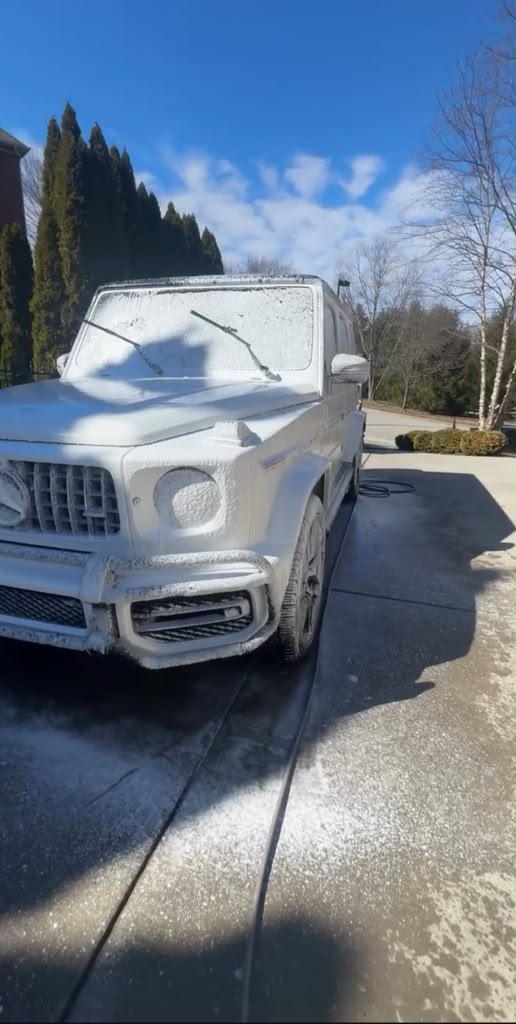 Luxury SUV covered in snow foam during wash