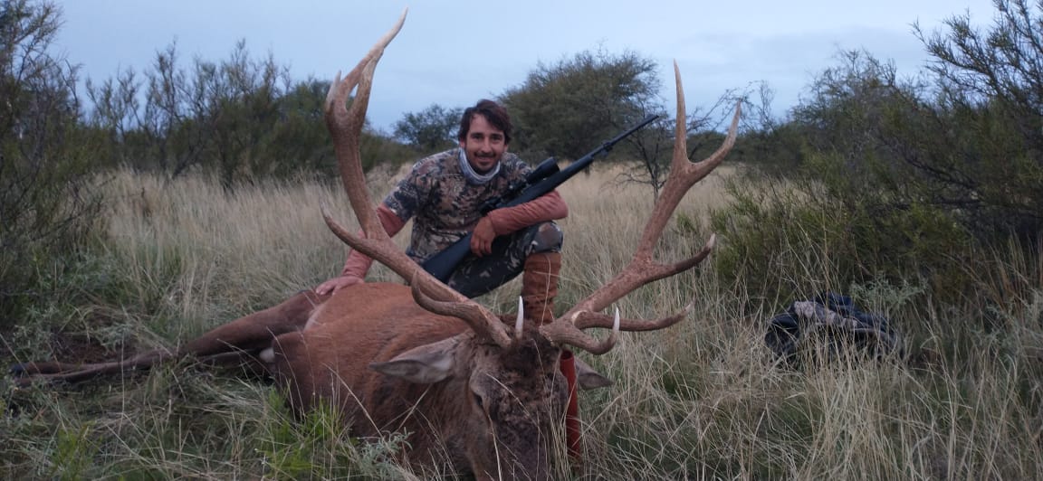 Successful hunt at Valle Daza - Hunter with trophy red deer in natural grassland setting