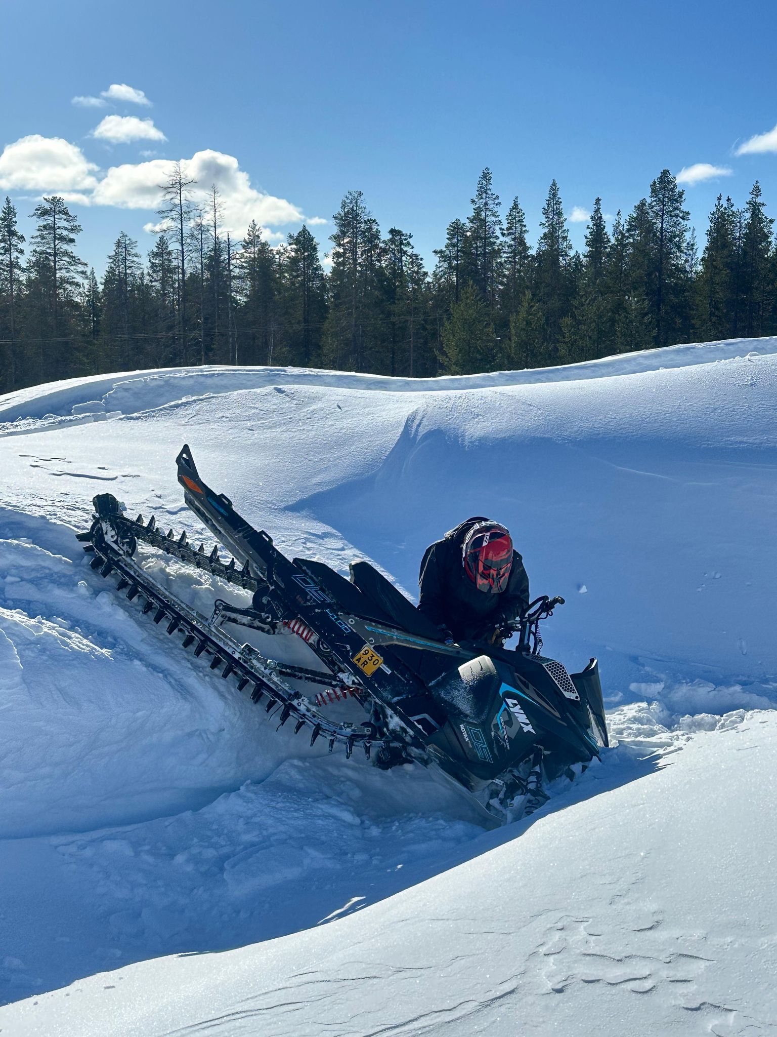 Snowmobile climbing steep snowy hill through pristine winter forest