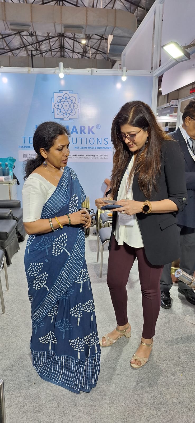Deepshikha speaking with woman in blue sari at exhibition
