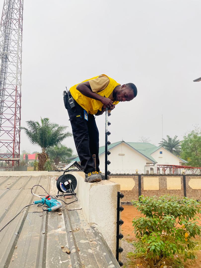 Technicien BECC installant un poteau de clôture électrique sur un mur de clôture