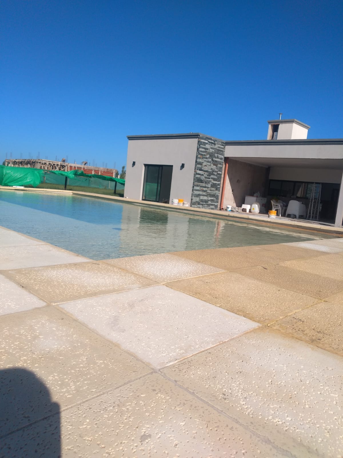 Vista lateral de la vivienda desde la pileta con galeria abierta y chimenea