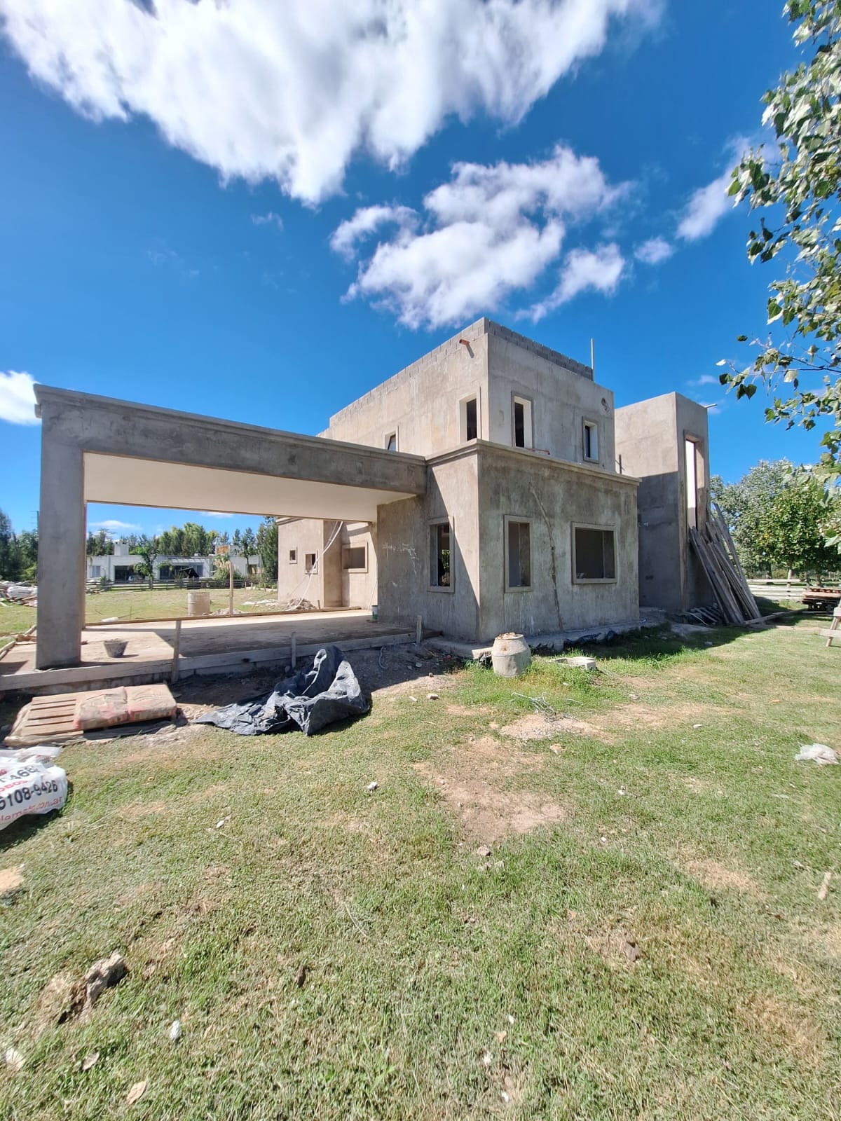 Vista lateral de la vivienda con pergola de hormigon, cesped y volumetria escalonada