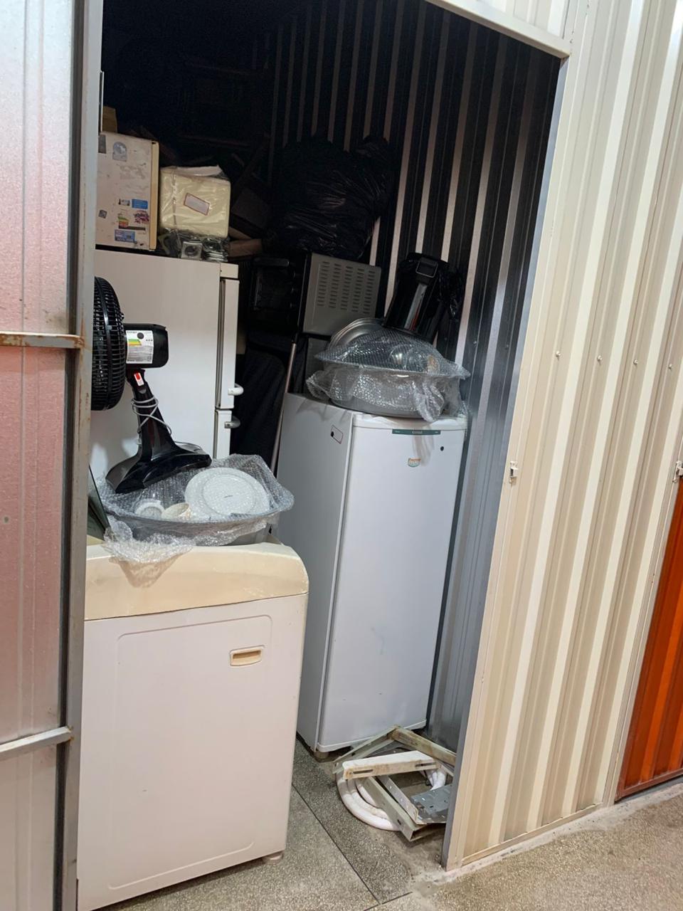 Box pequeno com geladeira, ventilador e caixas armazenadas