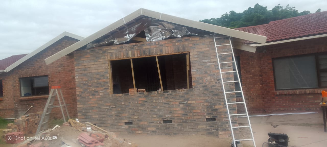 Side view of brick extension with white fascia boards and foil sarking installed, no tiles yet