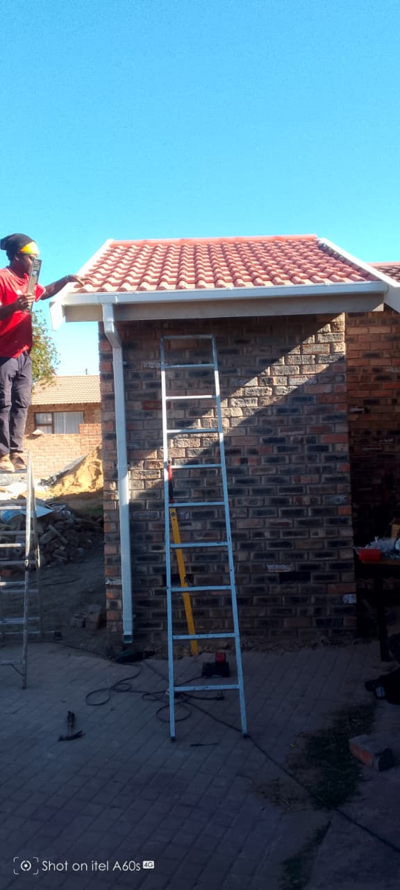 Completed tiled roof with white PVC guttering and downpipe installed, clear blue sky