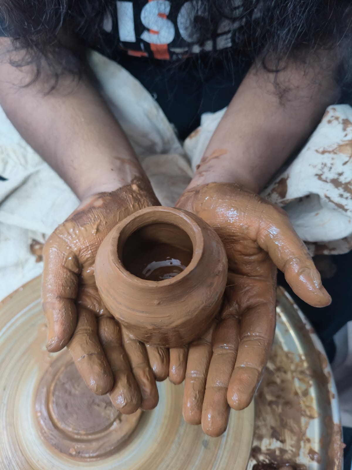 Hands holding freshly thrown clay pot