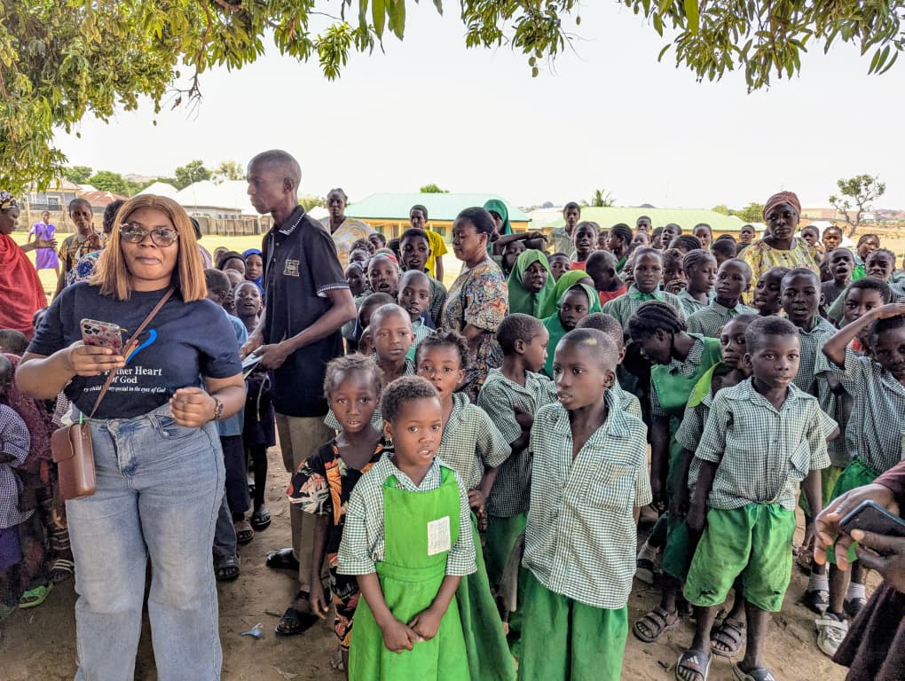 Children in green school uniforms with volunteers