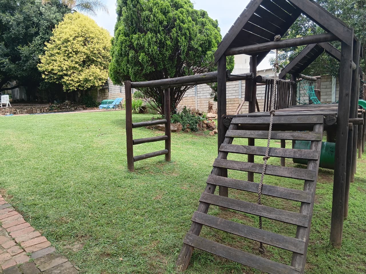 Beautiful garden with wooden jungle gym on well-maintained lawn