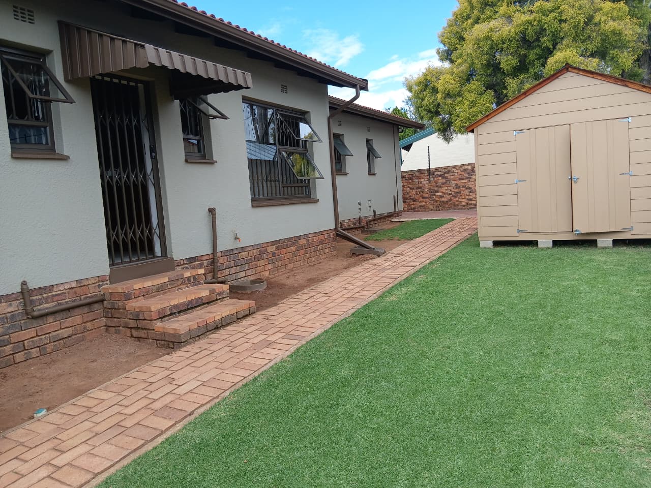 House exterior with neat lawn strip and brick pathway