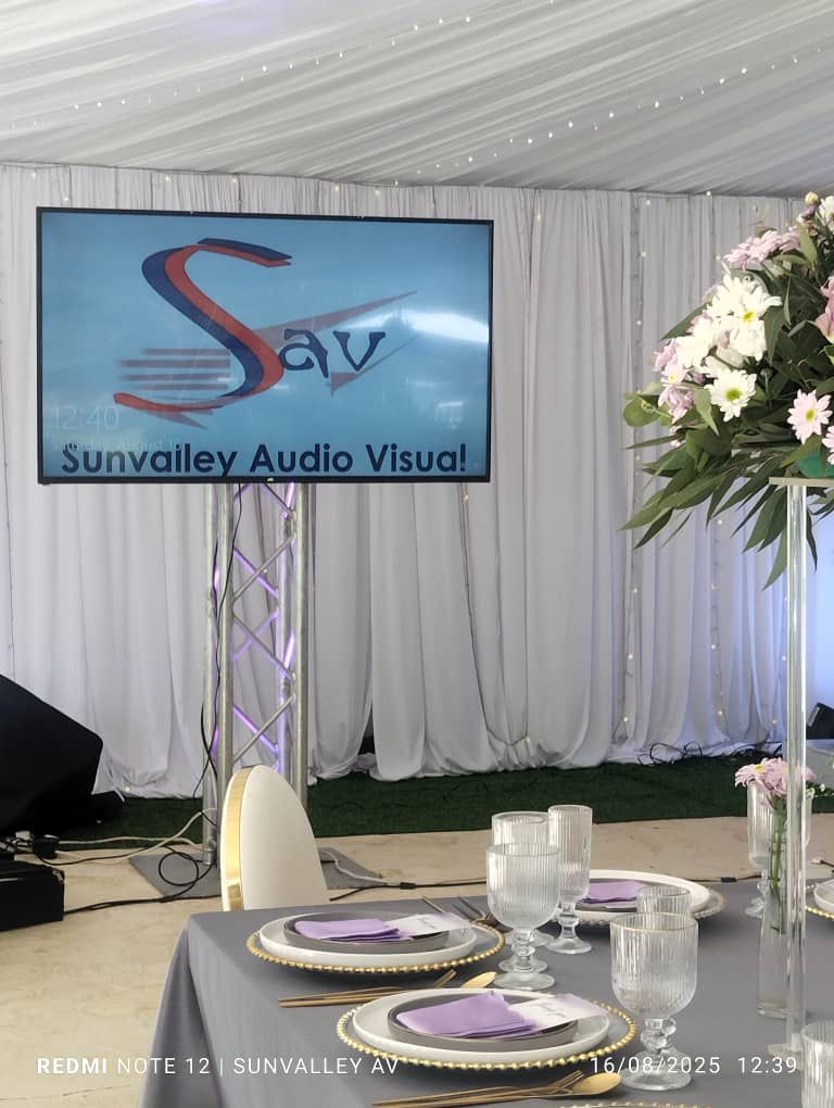 Event tent setup with Sunvalley Audio Visual branding on LED display, purple ambient lighting
