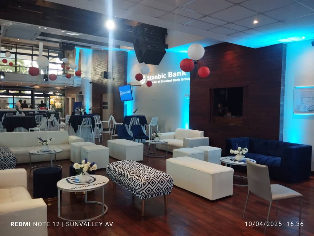 Professional corporate event with blue ambient lighting, sophisticated lounge seating, and AV production