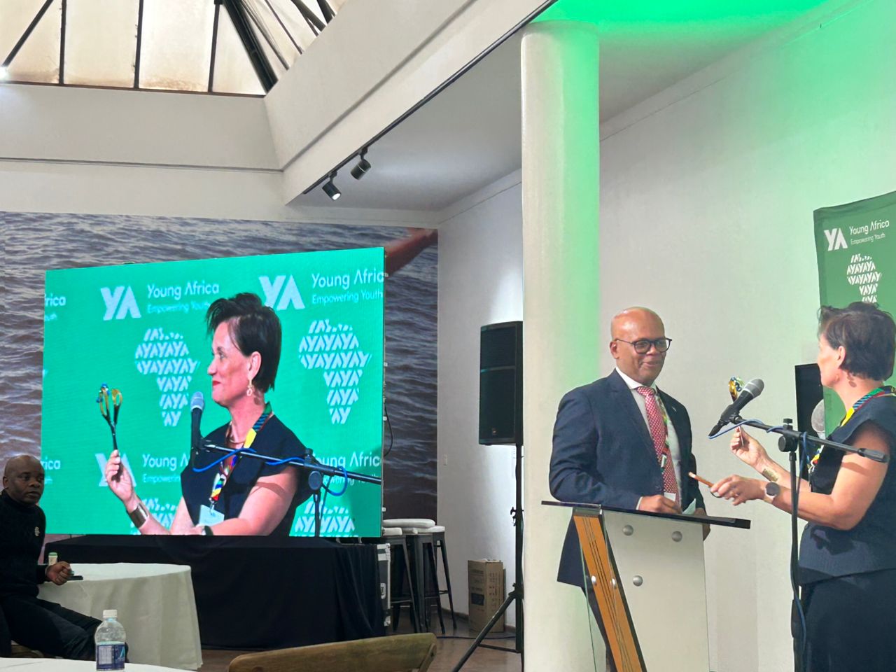 Young Africa event conference with woman speaking at microphone, large LED display with branding