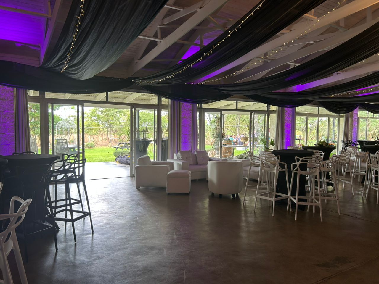 Large event space with purple ambient lighting, elegant furniture, outdoor garden integration