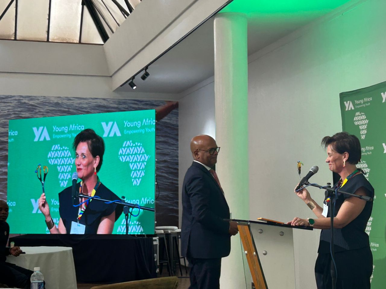Young Africa conference with professional LED display, woman speaking at microphone, branded backdrop