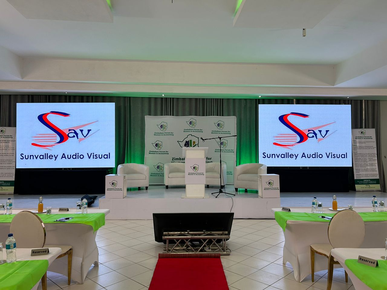Professional conference venue with dual LED screens displaying Sunvalley Audio Visual branding and stage setup