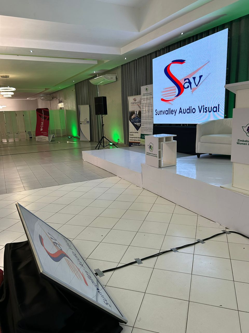 Conference venue with Sunvalley branding display, green ambient lighting, professional speaker setup