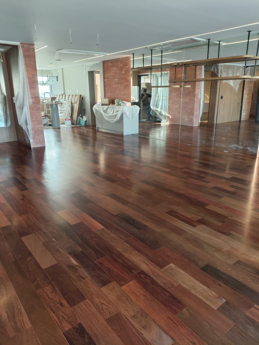 Espaço comercial amplo com piso de madeira brilhante e colunas de tijolo