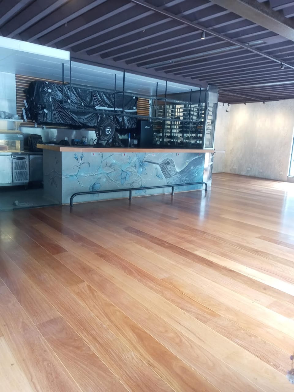 Restaurante com piso de madeira clara e bar decorado