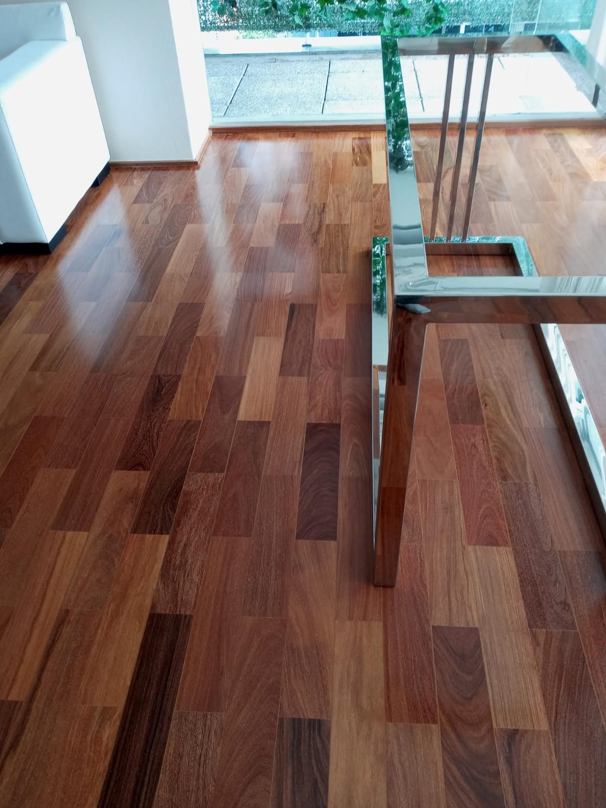 Sala de estar com piso de madeira e mesa de vidro