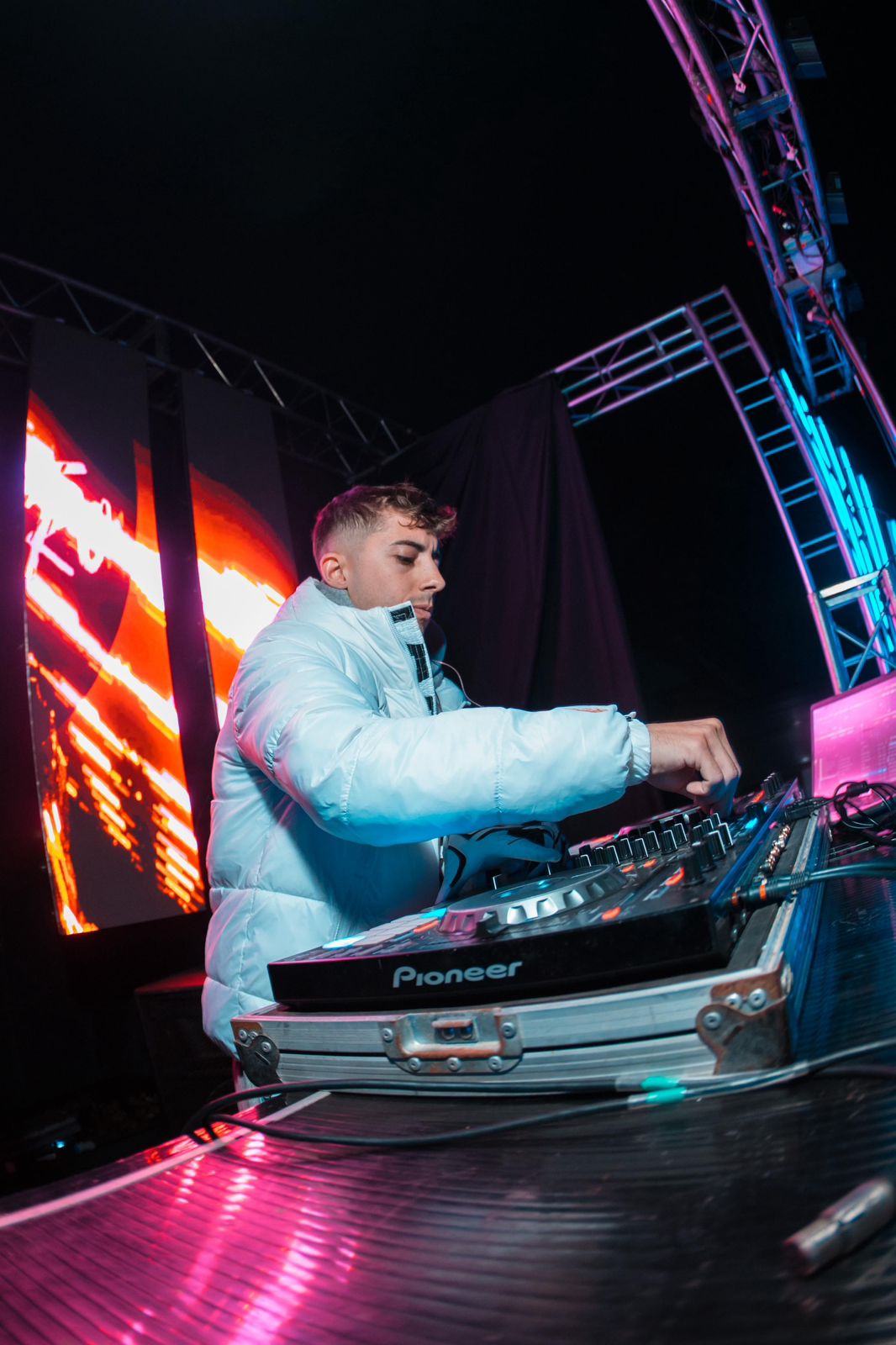 DJ con campera blanca y pantallas LED
