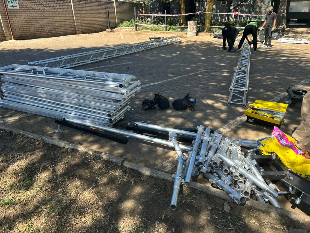 Professional aluminum truss components and metal staging equipment laid out for assembly
