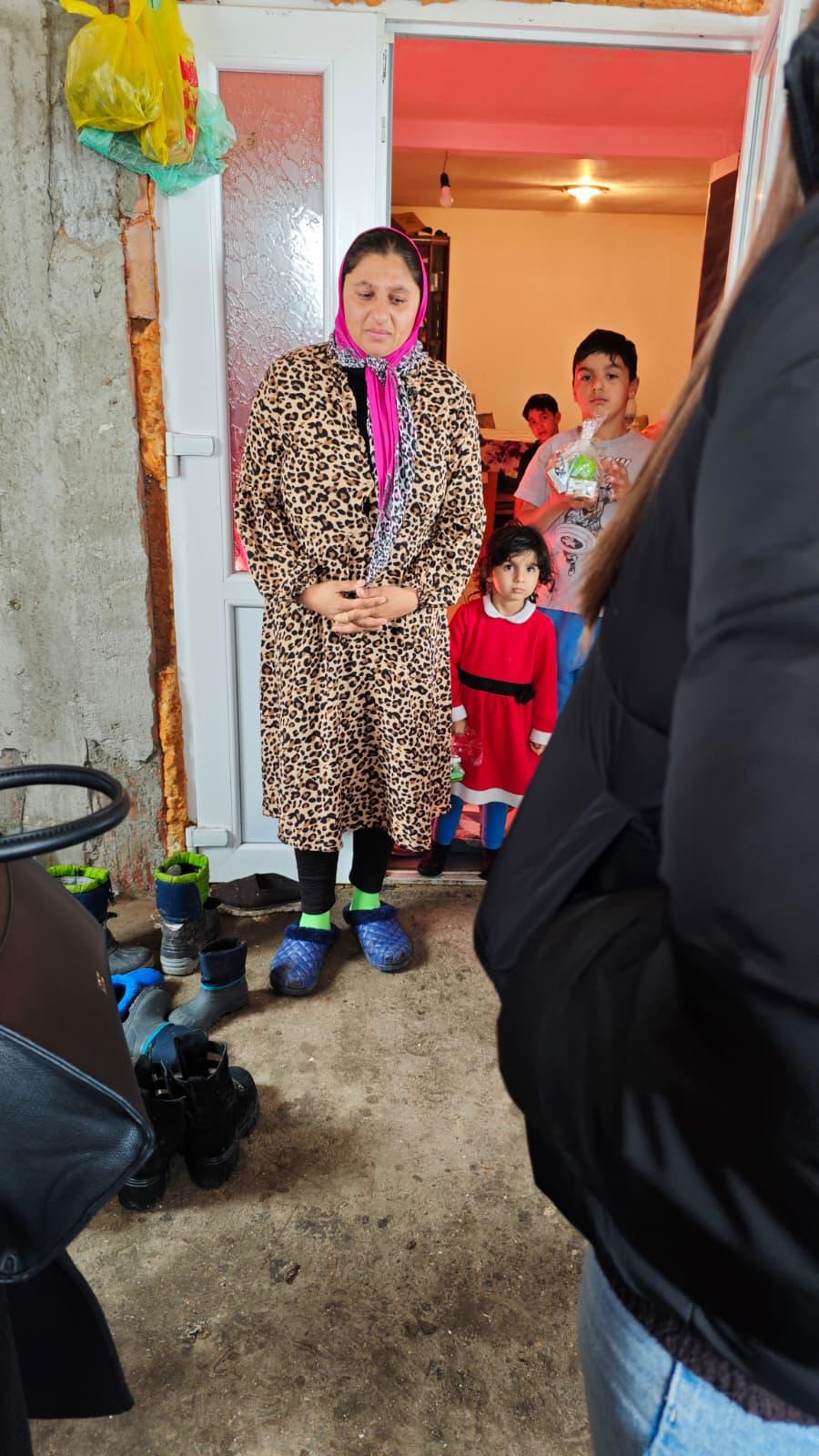 Mamă cu foulard și copii la ușa casei