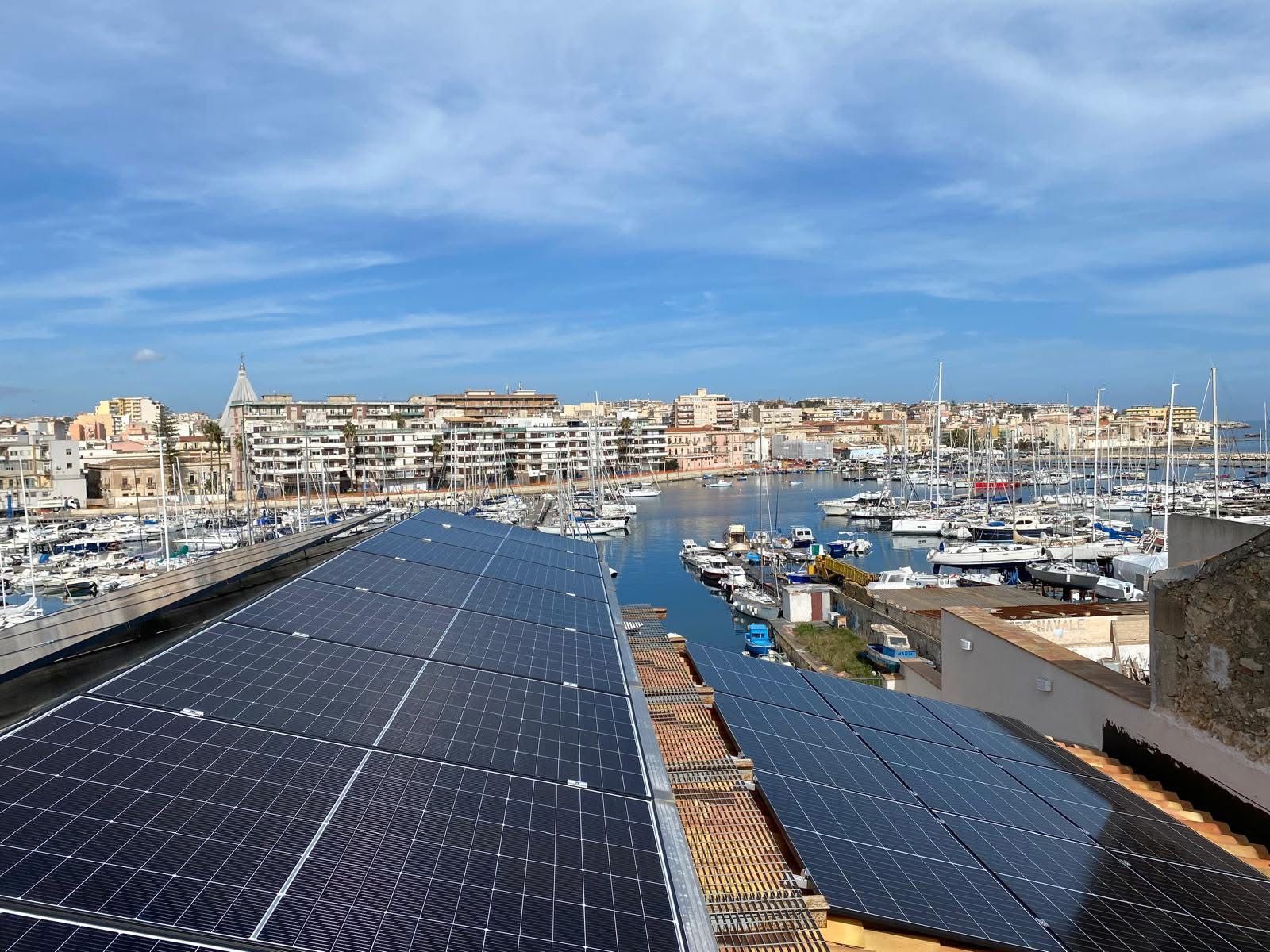 Pannelli solari su tetto con vista su porto turistico e citta costiera