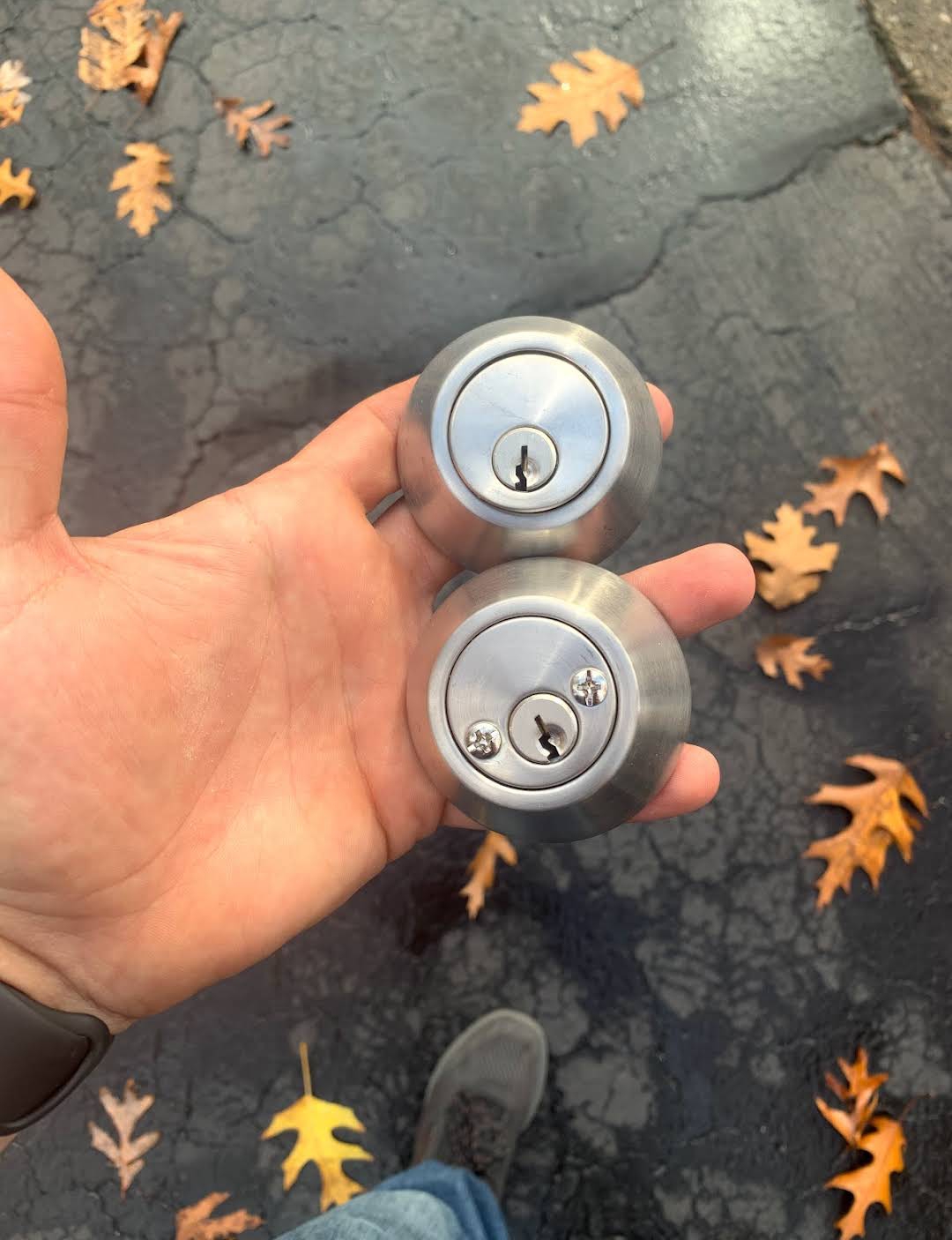 Two residential deadbolt locks being held for rekeying service