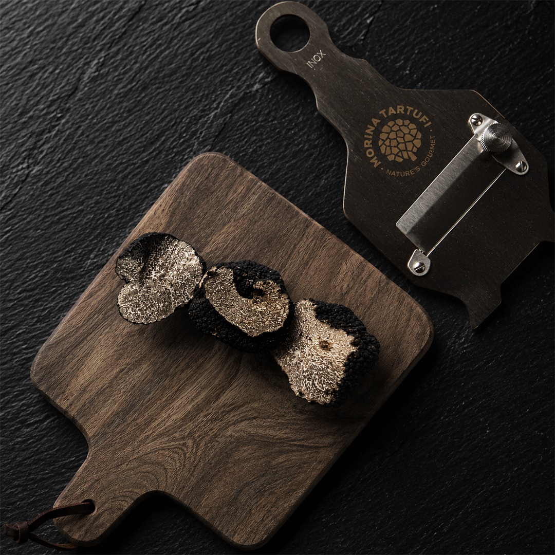 Sliced black truffles on wooden cutting board with Morina slicer