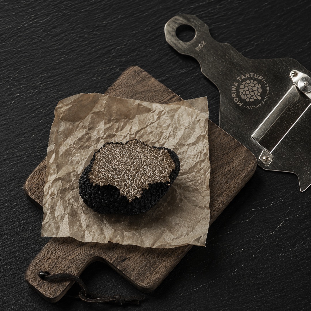 Black truffles on crumpled paper on wooden cutting board from above