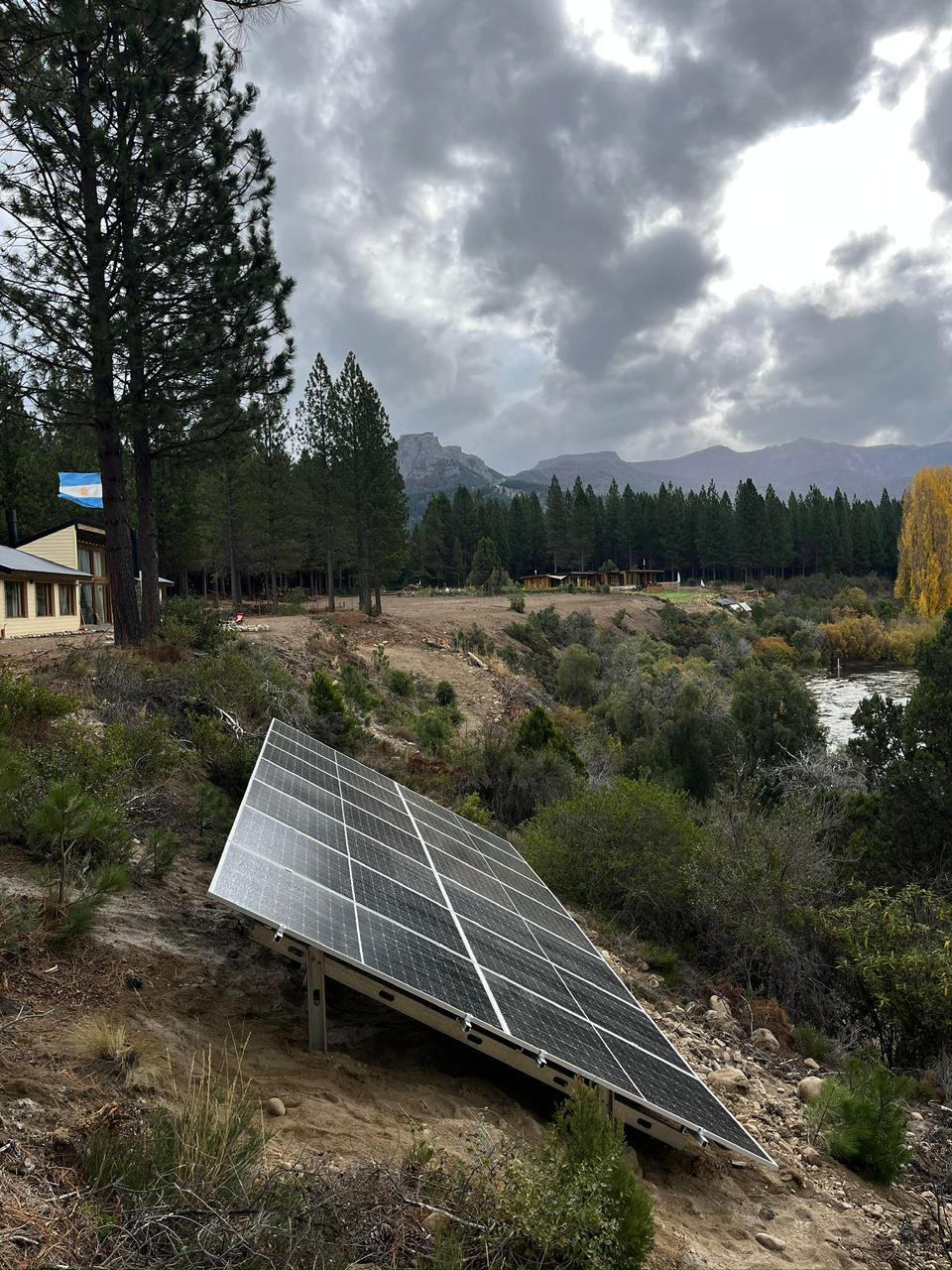 Paneles solares en terreno con río y paisaje patagónico